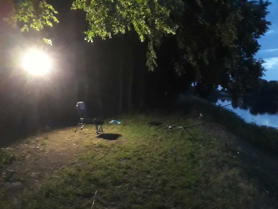 Noční rybolov na osvětleném břehu